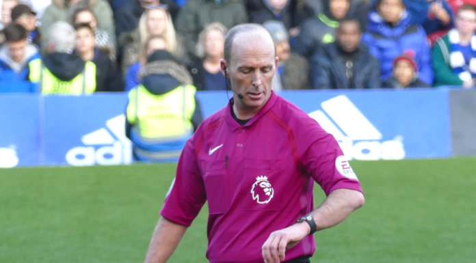 Mike Dean looks at his watch as he adds five extra minutes onto a Premier League game when he should only have added three.