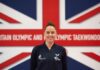 Paralympian Beth Munro smiling in front of GB Flag, which reads 'Britain Olympic and Paralympic Taekwondo'.