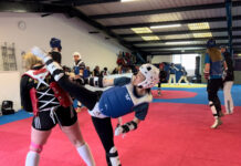 Taekwondo trainers in action at Whiston Taekwondo. One woman executes a high kick.