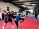 Taekwondo trainers in action at Whiston Taekwondo. One woman executes a high kick.