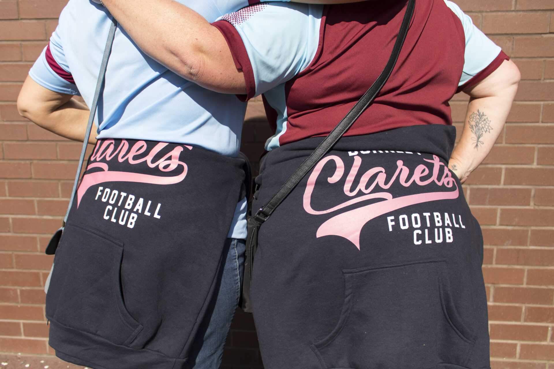 Two Burnley fans with Clarets hoodies tied around their waists