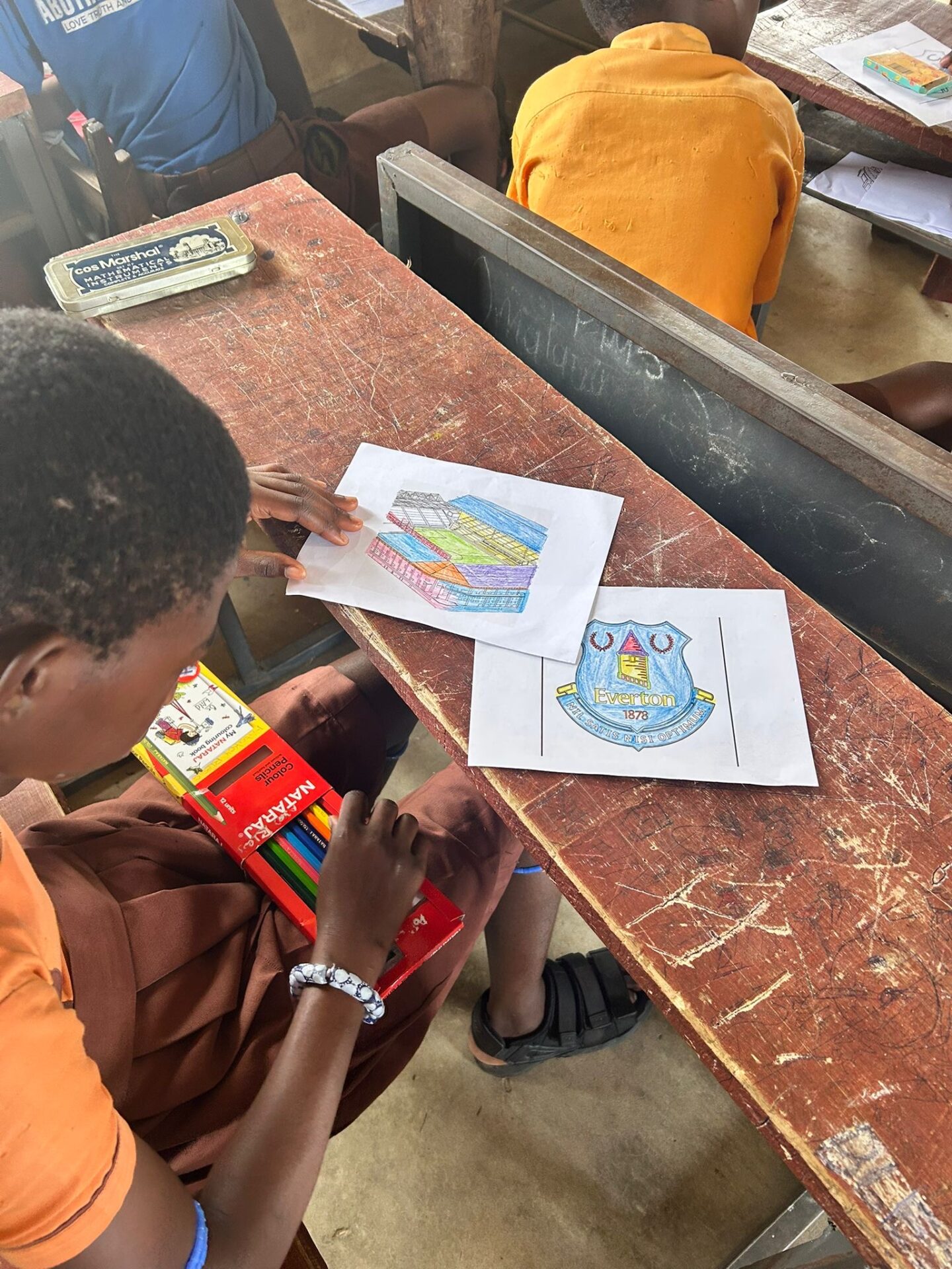 Child in Ghana colouring Everton crest. Pic by Danny Prentice.